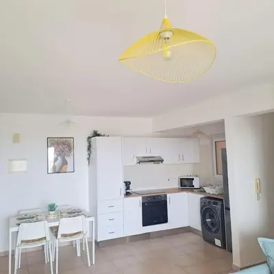 a kitchen with white cabinets and a table with chairs at CyPresa Sweet Home Oroklini in Larnaka