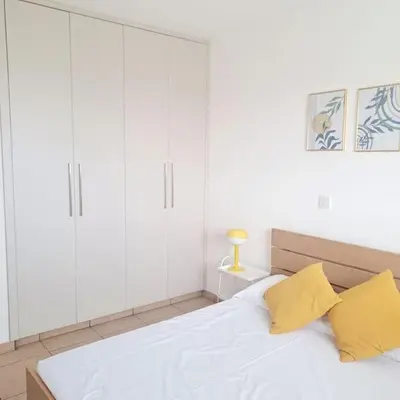 a bedroom with white cabinets and a bed with yellow pillows at CyPresa Sweet Home Oroklini in Larnaka