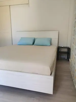 a white bed with blue pillows in a bedroom at The Little House in Voroklini