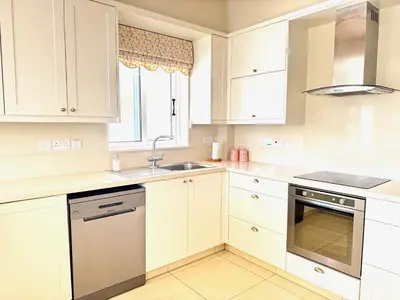 a white kitchen with white cabinets and a sink at Hephaestus Family Villa, Ayia Triada Beach in Paralimni