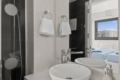 a white bathroom with two sinks and a shower at Serenity Waves Villa 21 in Sophtadhes