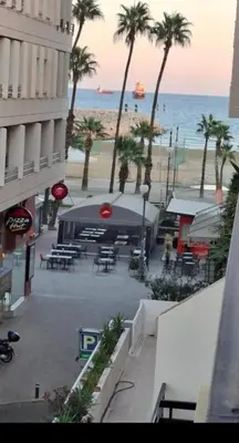 a view of a beach with palm trees and a tent at By The Way Apartment 1 in Larnaka