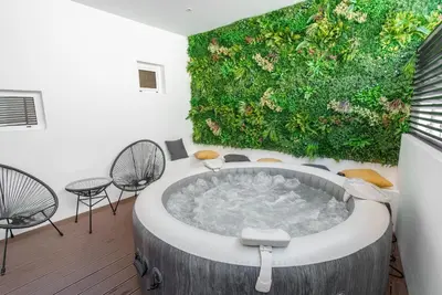 a bathroom with a large tub with a green wall at Kition Urban Suite 2 in Larnaka
