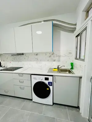 a white kitchen with a sink and a dishwasher at Tower Court rooms in Larnaka