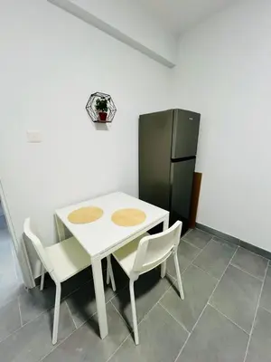 a white table with two chairs and a refrigerator at Tower Court rooms in Larnaka