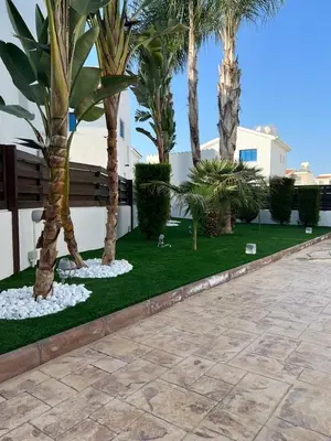 a garden with palm trees and a bench at Villa Alexander The Great in Protaras