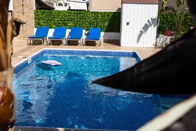 a swimming pool with blue chairs in a yard at Villa Alexander The Great in Protaras
