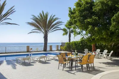 a patio with a table and chairs next to a pool at Luxury Villa With Special Sea Views in Meneou