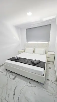 a white bedroom with a large bed in a room at Urban Comfort Apartment in Larnaka