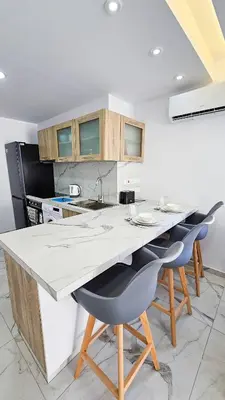a kitchen with a white counter and some chairs at Urban Comfort Apartment in Larnaka