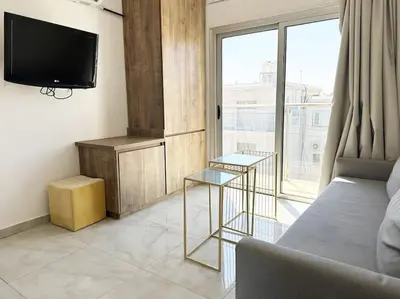 a living room with a couch and a large window at Alice Studio Holiday Apartment - Ayia Napa in Ayia Napa
