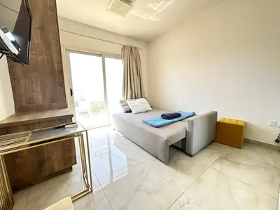 a living room with a bed and a large window at Alice Studio Holiday Apartment - Ayia Napa in Ayia Napa