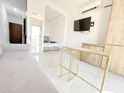 a living room with a table and a tv on a wall at Alice Studio Holiday Apartment - Ayia Napa in Ayia Napa