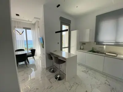 a white kitchen with a table and a dining room at The Address -Beachfront 2 Bedroom Residence in Limassol