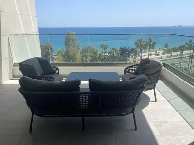 a balcony with a table and chairs and a view of the ocean at The Address -Beachfront 2 Bedroom Residence in Limassol