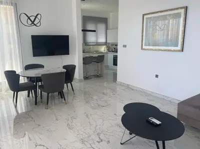 a living room with a table and chairs and a kitchen at The Address -Beachfront 2 Bedroom Residence in Limassol