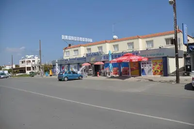 a blue car parked in front of a building on a street at Niove Budget One-Bedroom Apartment in Paralimni