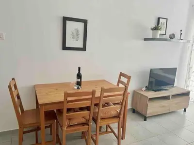 a dining room table with a bottle of wine and a television at Niove Budget One-Bedroom Apartment in Paralimni