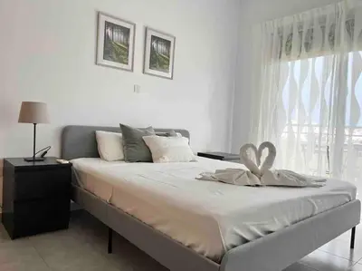 a white bedroom with a large bed and a window at Niove Budget One-Bedroom Apartment in Paralimni