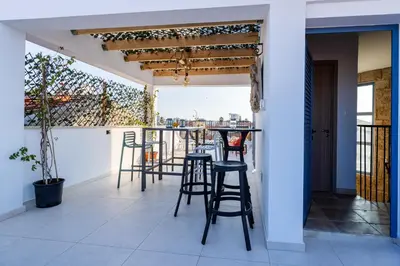 a bar on the balcony of a house with stools at Le Voyageur By the Sea - Furnished Rooms in Larnaka