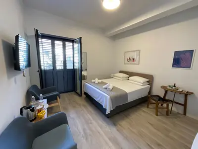 a bedroom with a bed and two chairs and a tv at Le Voyageur By the Sea - Furnished Rooms in Larnaka