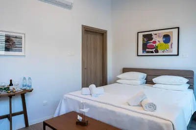 a bedroom with a bed with white sheets and a table at Le Voyageur By the Sea - Furnished Rooms in Larnaka