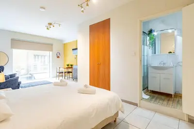 a bedroom with a large white bed and a bathroom at Charming studio with reading nook & city view in Nicosia