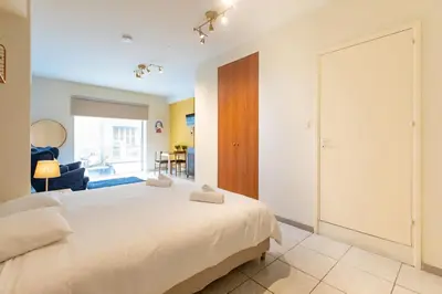 a bedroom with a large white bed and a living room at Charming studio with reading nook & city view in Nicosia