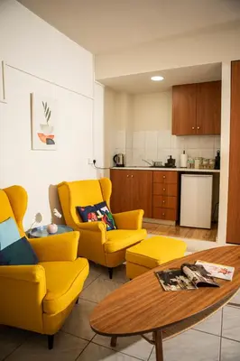 a living room with two yellow chairs and a table at Spacious studio located in the pedestrian zone in Nicosia