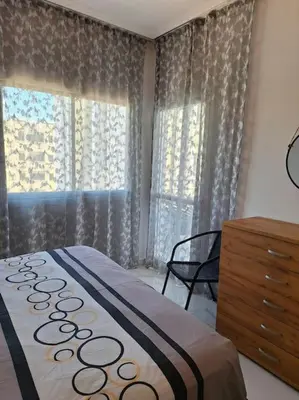 a bedroom with a bed and a dresser and two windows at Luxury one bedroom - seafront in Limassol