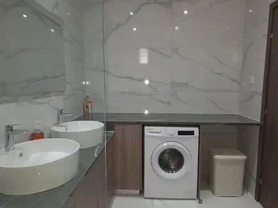 a bathroom with a sink and a washing machine at Luxury one bedroom - seafront in Limassol