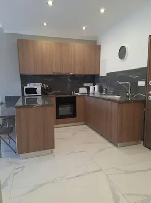 a large kitchen with wooden cabinets and a sink at Luxury one bedroom - seafront in Limassol