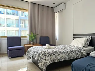 a bedroom with a bed and two chairs and a window at Albert's Apartment Center 21 in Larnaka