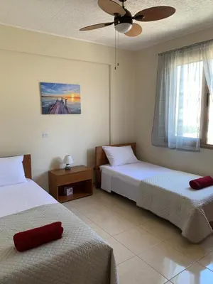 a bedroom with two beds and a ceiling fan at Seascape apartment in Larnaka