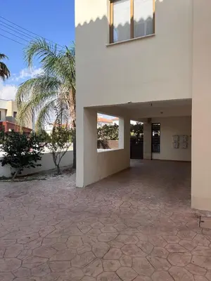 a white building with a courtyard with a palm tree at Seascape apartment in Larnaka