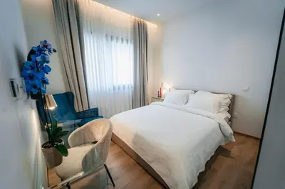 a bedroom with a white bed and a chair at TG NEW Luxury Private Resort & SPA Villas - Heated Salty Swimming Pool, Outdoor Jacuzzi, Sauna, Exotic Garden in Limassol