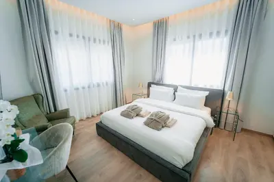 a bedroom with a large white bed and a chair at TG NEW Luxury Private Resort & SPA Villas - Heated Salty Swimming Pool, Outdoor Jacuzzi, Sauna, Exotic Garden in Limassol
