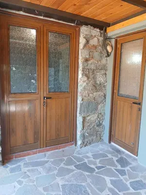 a pair of wooden doors on a stone wall at George's House in Askas