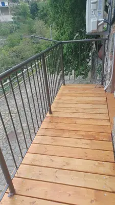 a wooden walkway with a metal railing on a balcony at George's House in Askas