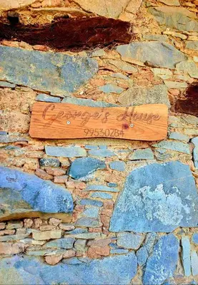 a wooden sign on the side of a stone wall at George's House in Askas