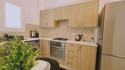 a kitchen with wooden cabinets and a table and a refrigerator at STAY Novel Apartment in Larnaka