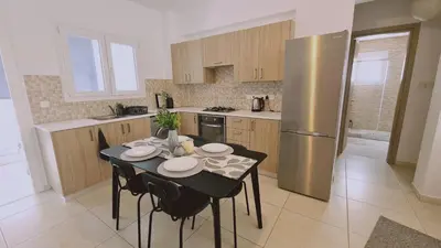 a kitchen with a table and a stainless steel refrigerator at STAY Novel Apartment in Larnaka