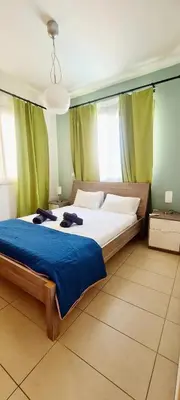 a bedroom with a large bed with a blue blanket at Crystal aptmnt next to the beach in Protaras