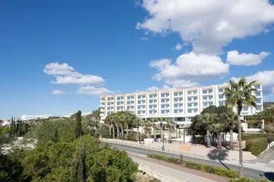 a large white building with palm trees and a road at Cyprotel Florida in Ayia Napa