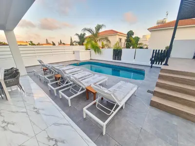 a patio with lounge chairs and a swimming pool at Sunshine Villa Ayia Napa in Ayia Napa