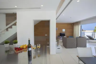 a living room with a table with wine glasses at Goodness Villa offers Magnificent Coastal Views in Protaras