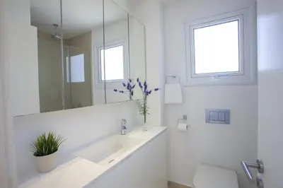 a white bathroom with a sink and a mirror at Goodness Villa offers Magnificent Coastal Views in Protaras