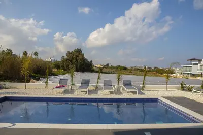 a pool with chaise lounge chairs and a swimming pool at Brand New Luxurious Villa With Pool in Protaras