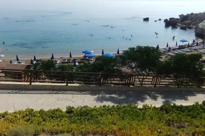 a beach with umbrellas and people swimming in the water at Olivia One Bedroom Apt renovated 2026 in Paralimni