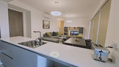 a kitchen with a sink and a living room at STAY Diamond Apartment in Larnaka